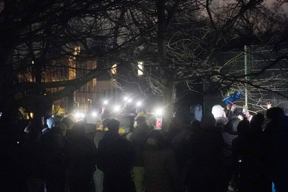 People attending a night vigil in Downhills Park, holding up phones with flashlights.