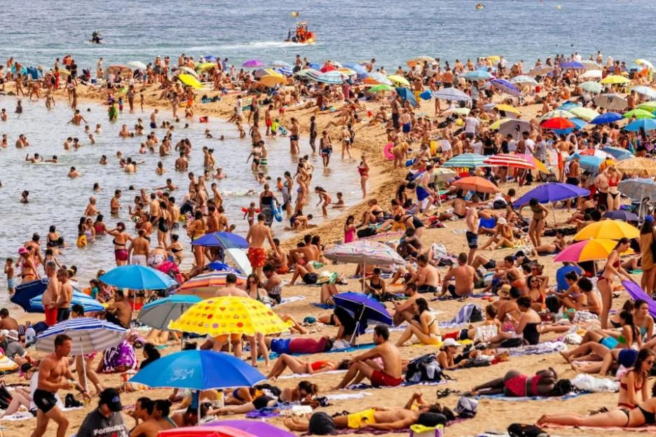 Crowds of tourists relaxing on Barceloneta beach in Barcelona, Spain.