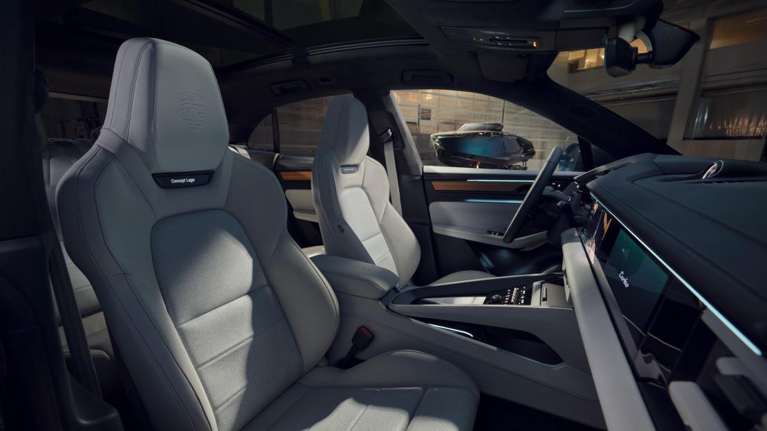 Interior of a car with light gray seats, showing a panoramic sunroof and a view of a boat outside.