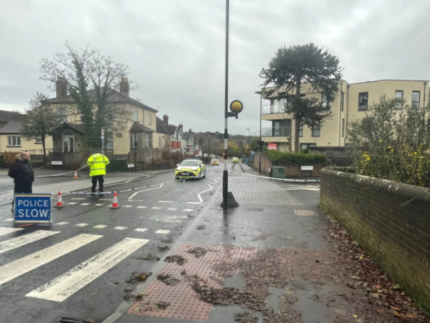Police scene on a wet street with officers and a marked car.