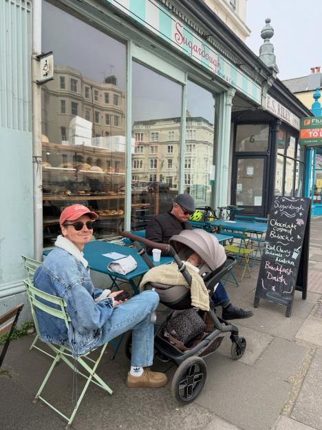 Joe Sugg and Dianne Buswell with their baby in a stroller outside a bakery.