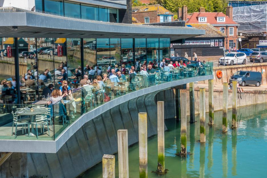RockSalt Restaurant in Folkestone Harbour, Kent, with a cantilevered patio full of diners.