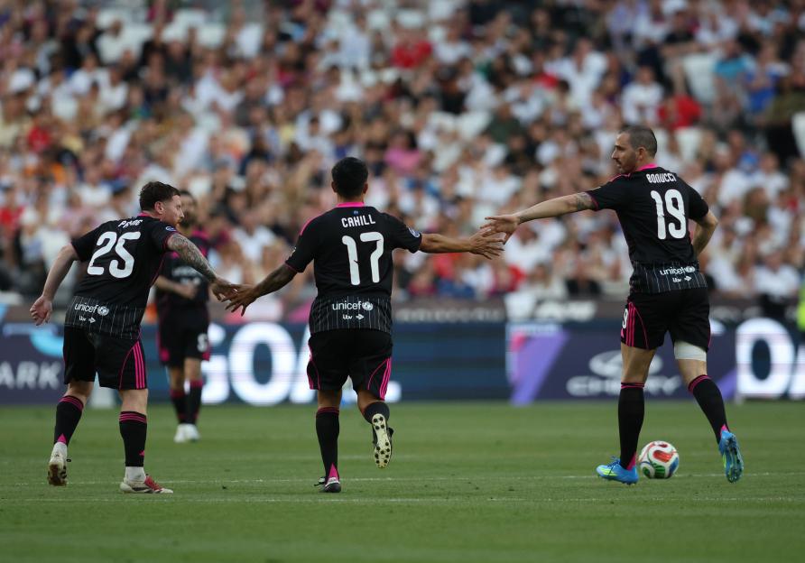 Soccer Aid players shake hands on the field.