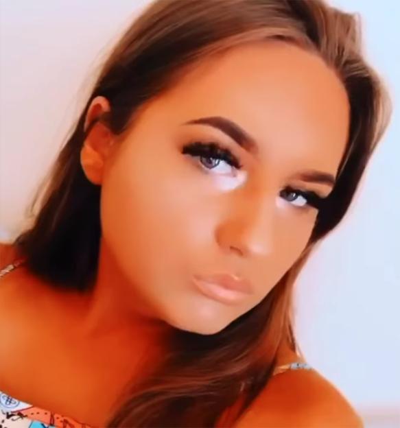 Courtney Angus, a young woman with long brown hair and full makeup, looking slightly away from the camera.