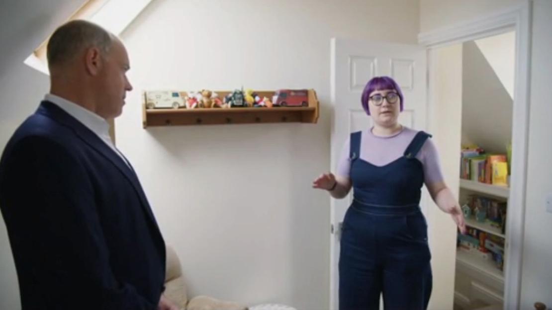A man in a suit looking at a woman with purple hair in a child's room.