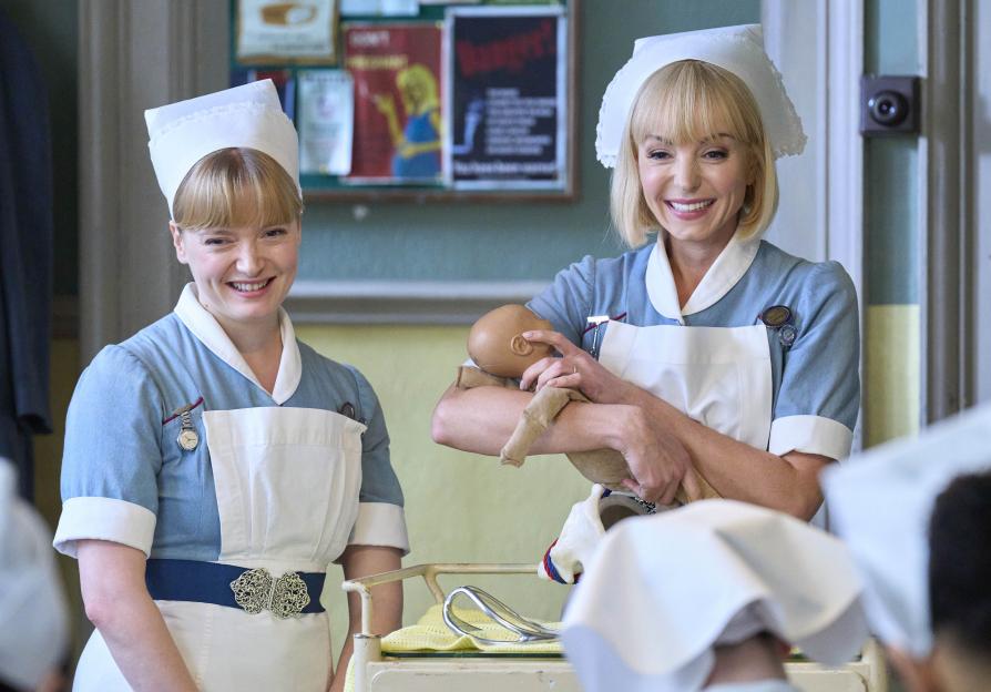 Trixie Franklin and Rosalind Clifford in their nurse uniforms, one holding a baby doll.
