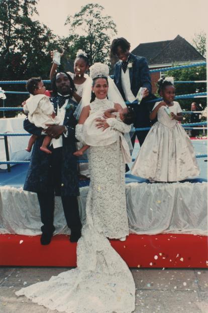 a bride and groom pose with their children in a boxing ring