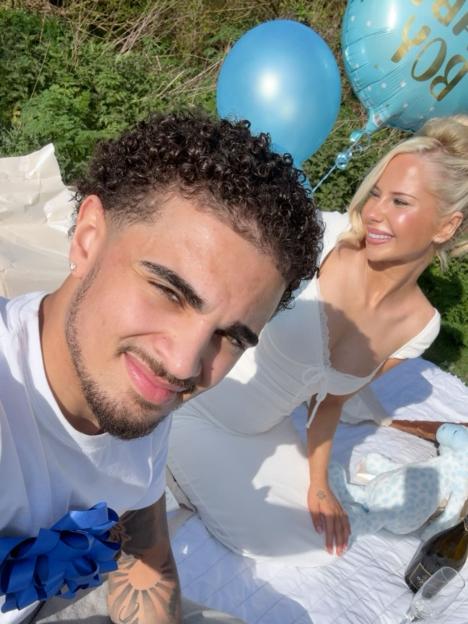 Elsa Rae and Marcus at a gender reveal picnic with blue balloons.