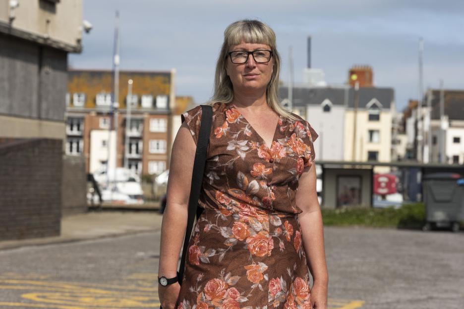 Emma Smart, an eco-activist, stands outdoors wearing a brown floral dress and glasses.