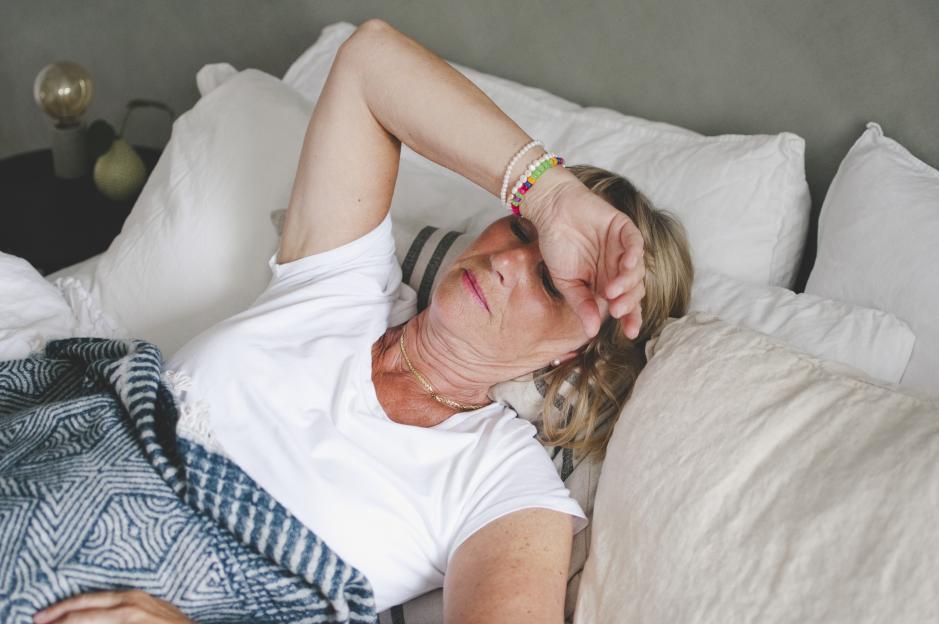 Senior woman suffering from a cold, lying in bed at home.