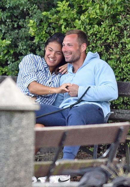 Emma Raducanu holding hands with a man on a park bench.