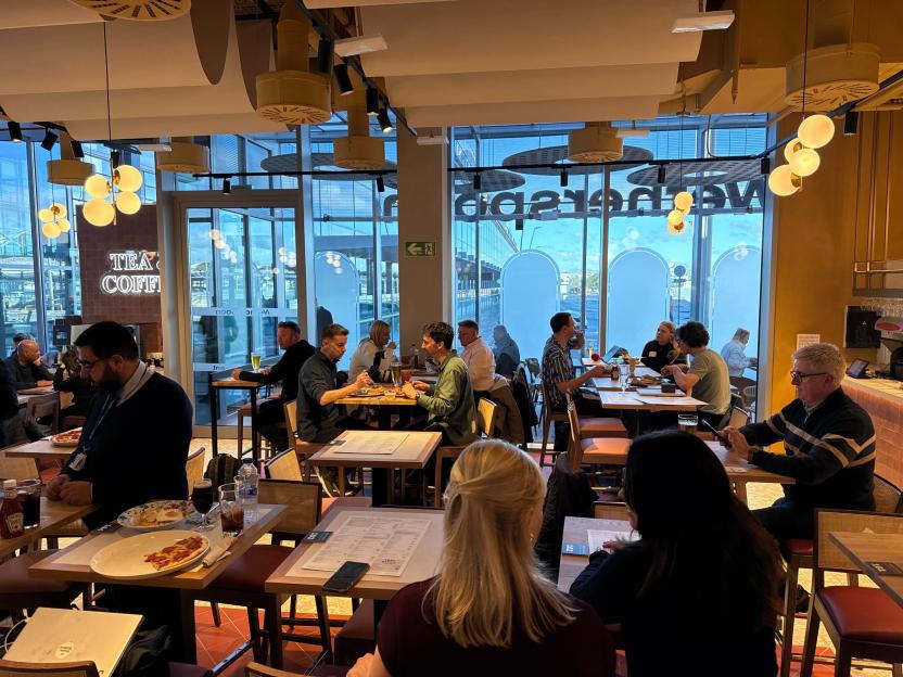 People dining in a restaurant with large windows overlooking an airport runway.
