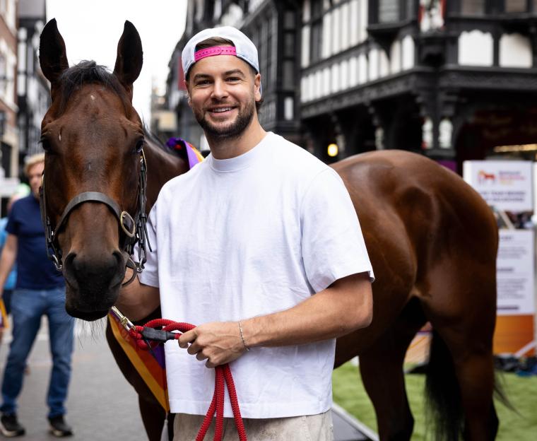 Television personality Chris Hughes poses with a racehorse in Chester city centre.
