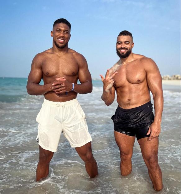 Two muscular men standing in the ocean.