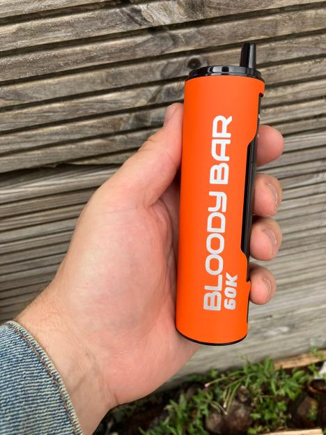 A hand holds an orange Bloody Bar 60K vape.