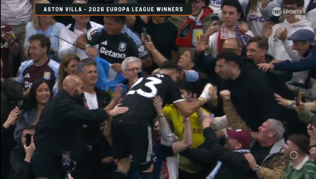 Soccer players in black uniforms celebrating with fans in the stands.