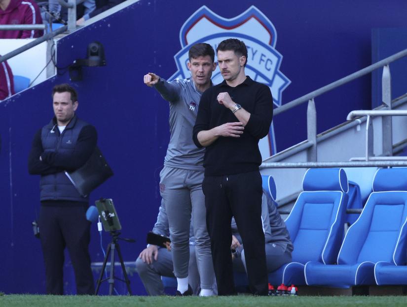 Cardiff City coach Tom Hutton points while speaking with interim manager Aaron Ramsey during a match.