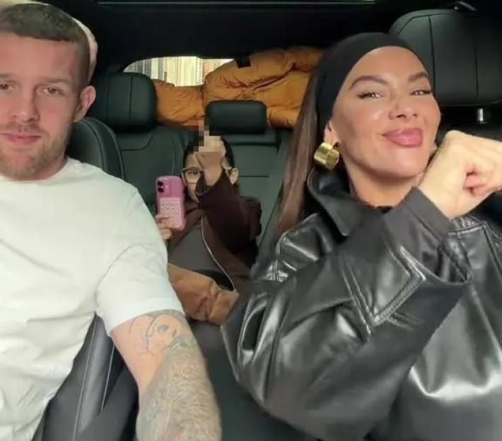 A man, a woman, and a young girl (partially censored) are in a car, with the woman smiling at the camera.