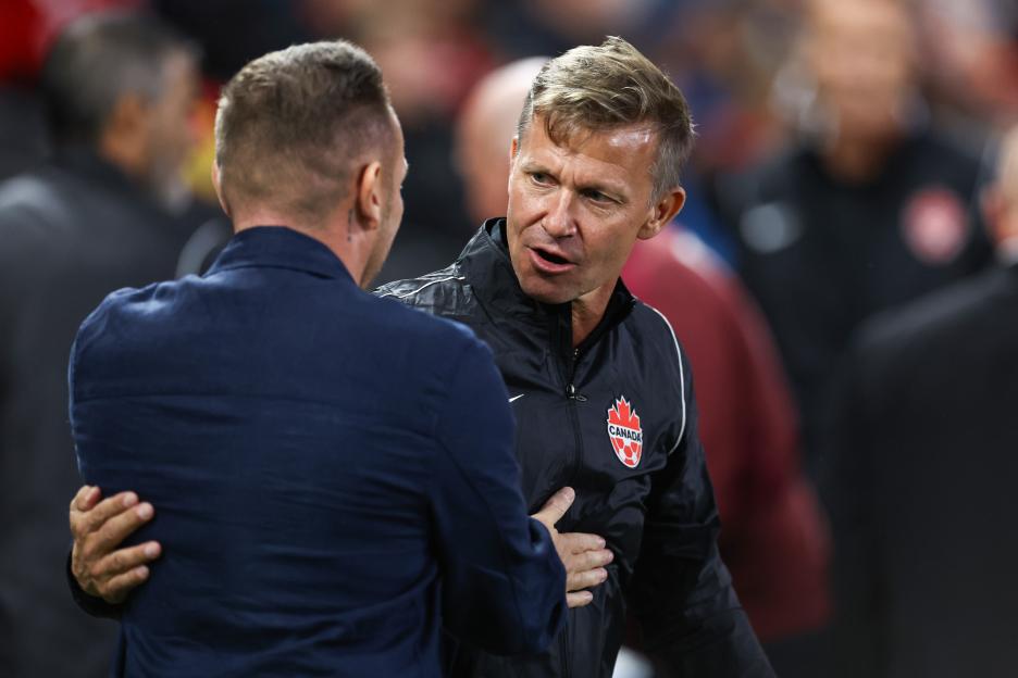 Craig Bellamy and Jesse Marsch, managers of Wales and Canada respectively, talking during a soccer match.