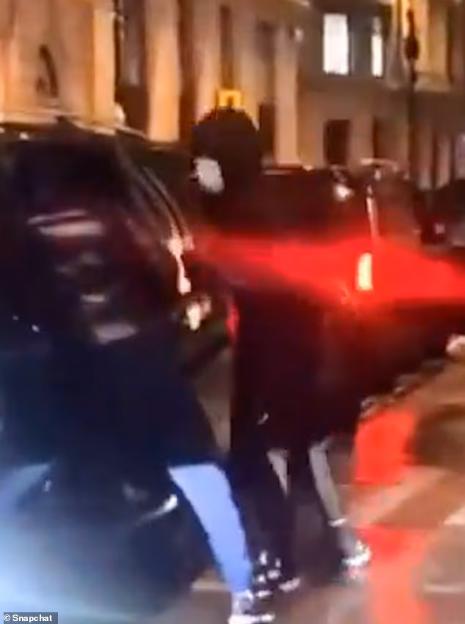 Two figures moving quickly on a street at night, with red and white lights from vehicles visible.