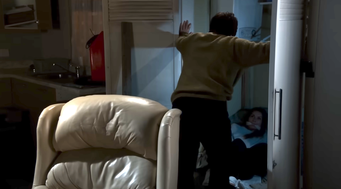 A man pushing a closet door shut, concealing a woman with a gag in her mouth.