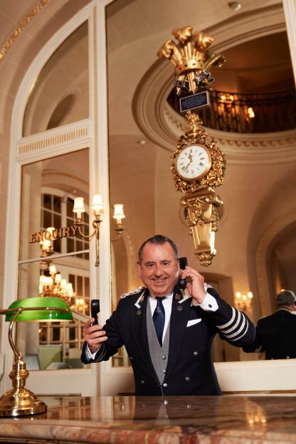 Michael De Cozar, Head Concierge at The Ritz, holding two phones in the hotel lobby.