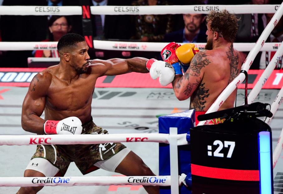 Anthony Joshua throws a punch at Jake Paul in a boxing match.