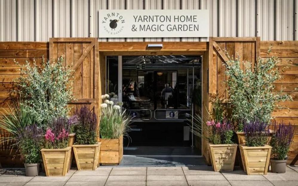 Entrance to Yarnton Home & Magic Garden with large planters containing various plants and flowers.