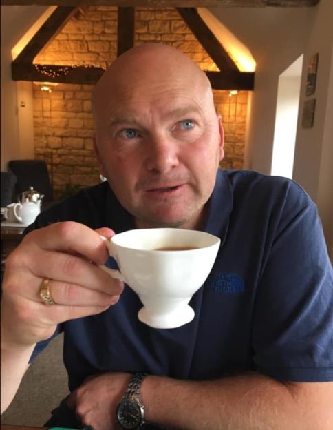 Kevin Dean, a man with a ring and watch, holds a teacup.