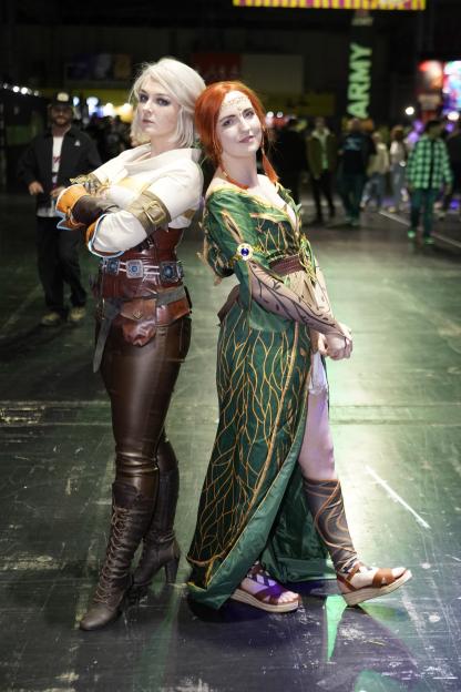 Two women cosplaying as Ciri and Triss from The Witcher at a gaming festival.