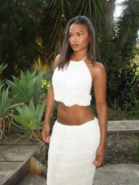 Layla Roye in a white halter top and matching skirt.