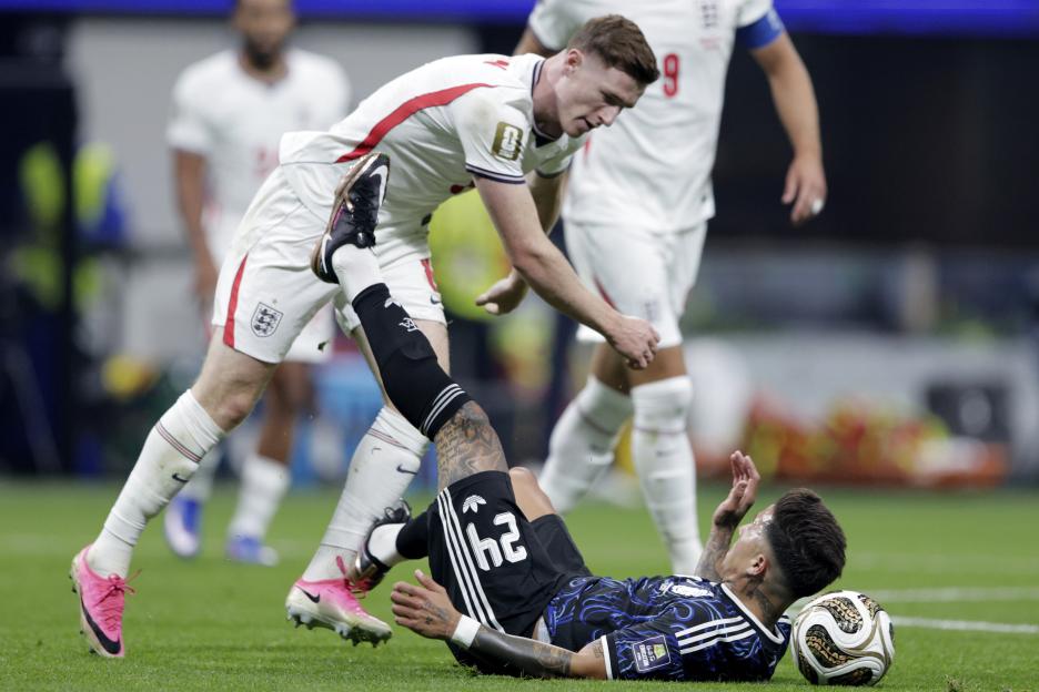 England's Elliot Anderson stands over Argentina's Enzo Fernandez, who is on the ground next to a soccer ball.