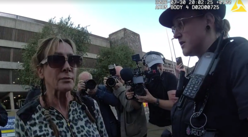 Pamela Gwinnett being arrested by officers from Greater Manchester Police at Manchester Airport, surrounded by journalists with cameras.
