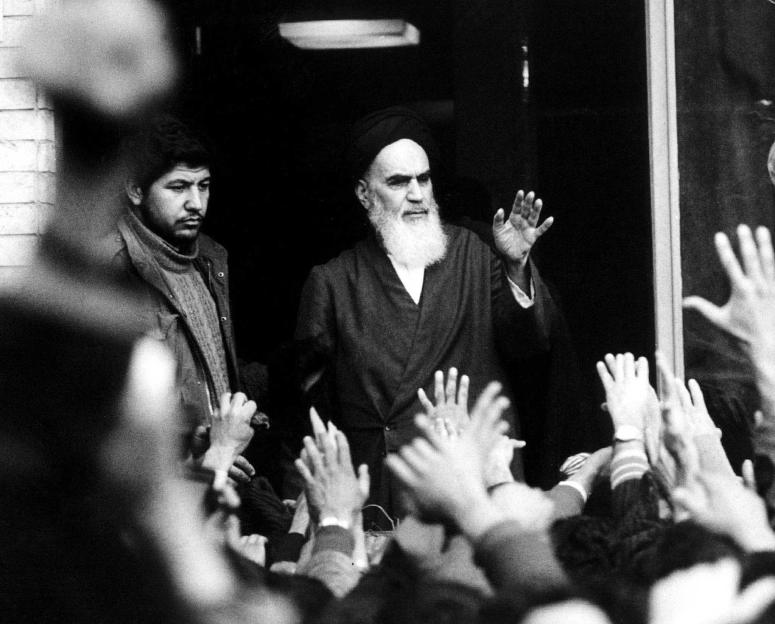 Ayatollah Khomeini speaking from a balcony with a crowd below.