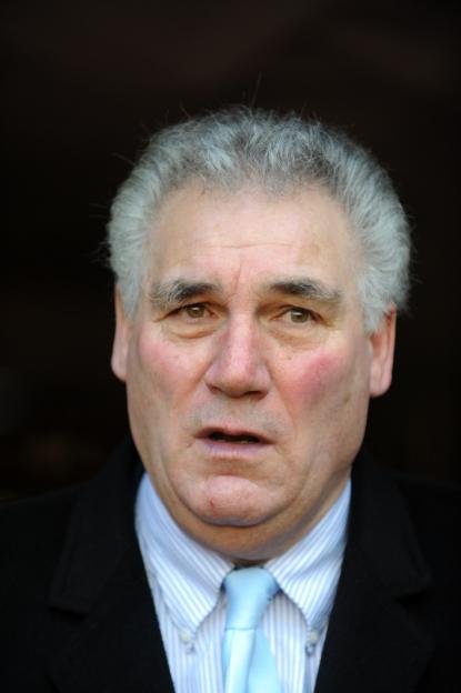 Headshot of a man with gray hair, a blue and white striped shirt, and a light blue tie.