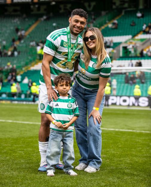 A male footballer with a medal, a woman, and a young boy, all in Celtic FC jerseys, stand on a green pitch.