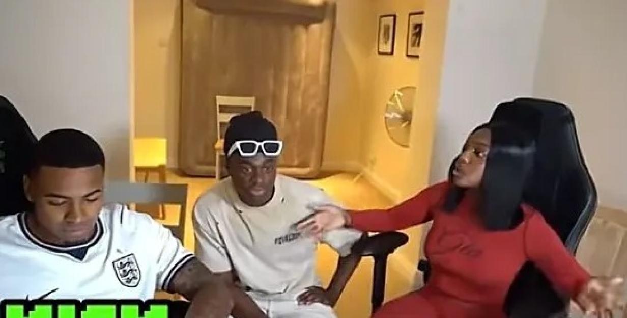 A man in a white jersey sits next to a man in a beige hoodie wearing sunglasses, and a woman in a red outfit is talking.