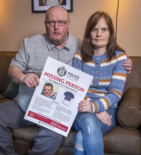 Parents holding a missing person poster of their son, Allan Bryant.