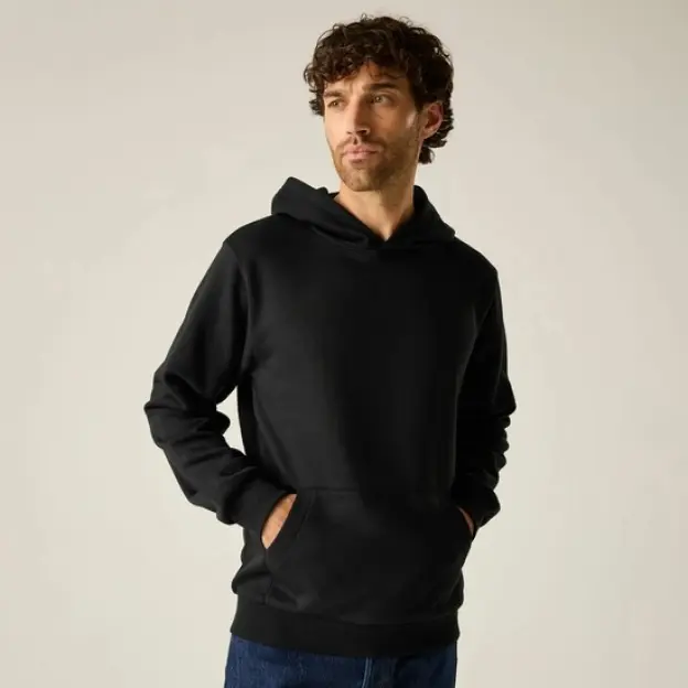 Man wearing a black hoodie with hands in the front pocket.