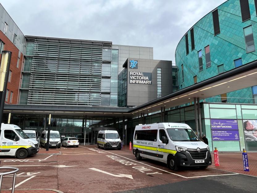 The Royal Victoria Infirmary in Newcastle upon Tyne with several NHS ambulances and patient transport service vans parked outside.
