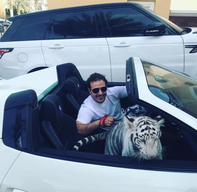 Wolfgang with a tiger in a white convertible car.