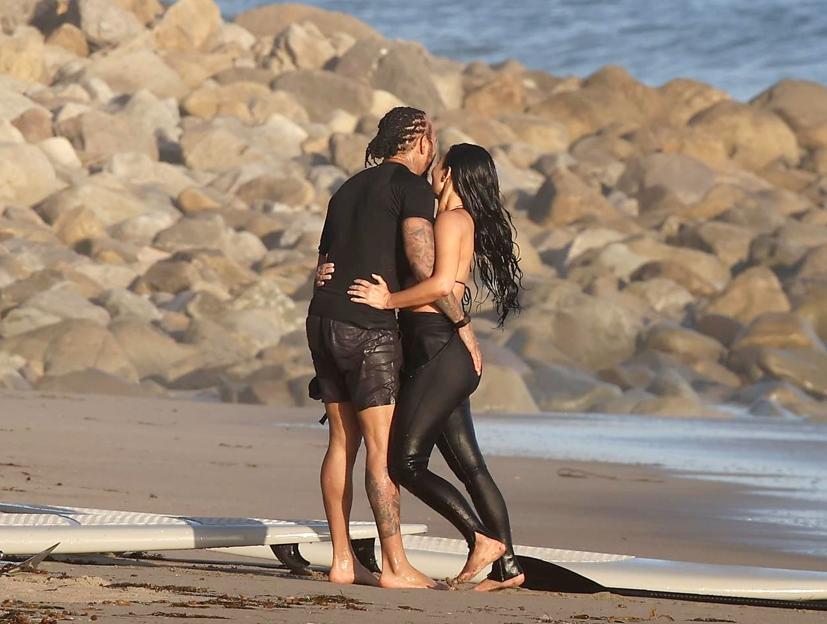 Kim Kardashian and Lewis Hamilton kissing on a beach.