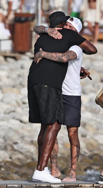 Michael Jordan and David Beckham embrace on a wooden pier.