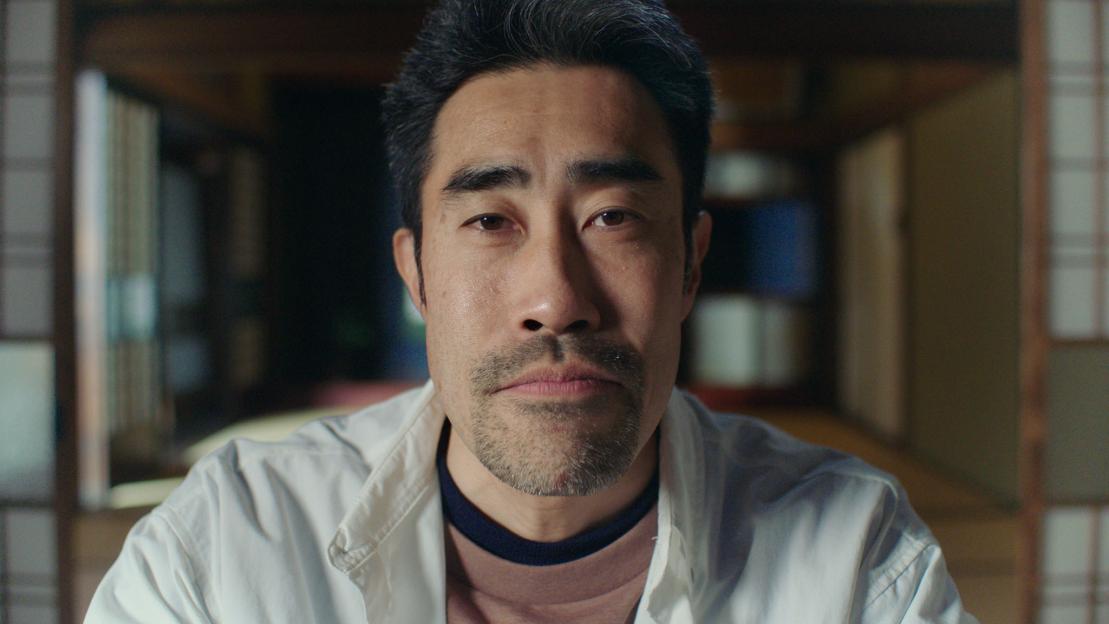 Close-up of Nasubi, the lead contestant from Storyville, looking directly at the camera with a neutral expression.