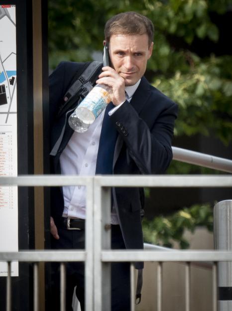 Tim Capron, a pilot, speaks on his phone while carrying a water bottle and a backpack.