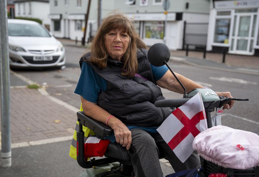 Woman on a mobility scooter with an English flag on the front.
