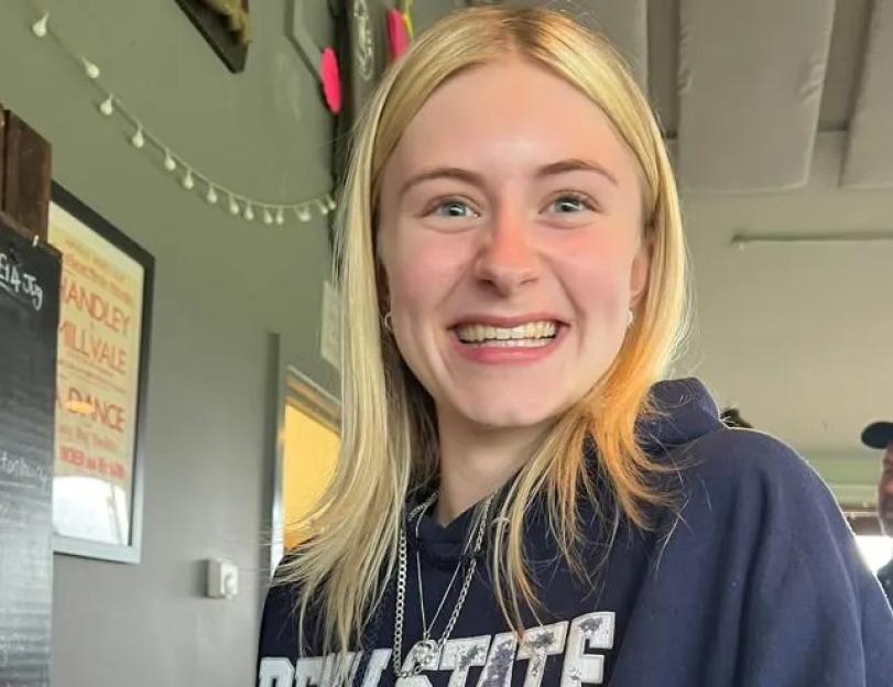 A smiling young woman, Laionie Kennard, holding a glass of Carlsberg beer.