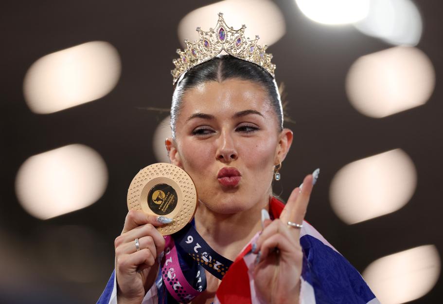 Gold medalist Amy Hunt with a tiara on her head, holding her medal and making a kissing face.