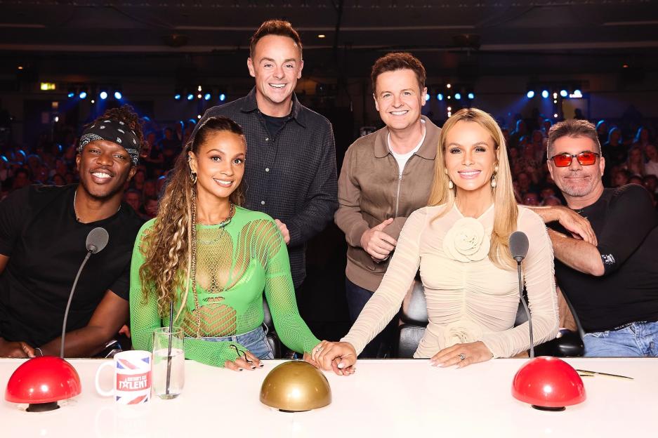 Judges and hosts of Britain's Got Talent Series 19 pose at the judges' desk in front of an audience.