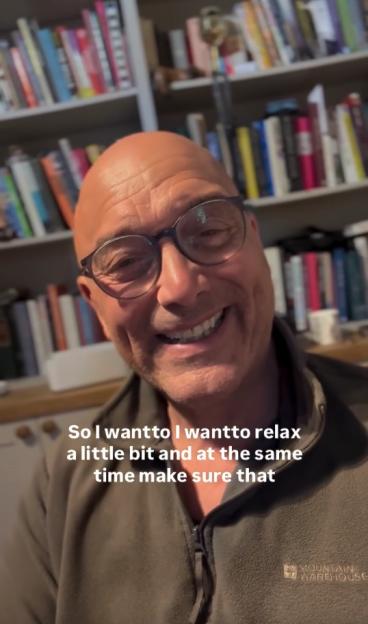 Gregg Wallace, bald and wearing glasses, smiling at the camera with bookshelves in the background.